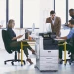Xerox® Série VersaLink® C7100, imprimante multifonctions couleur en situation au travail Equipe de travail dans un bureau avec des papiers imprimés et l'imprimante multifonctions couleur Xerox® Série VersaLink C7100