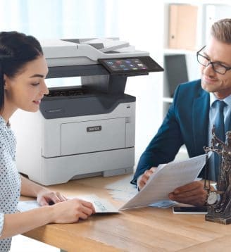 Un homme et une femme assis à une table, engagés dans une conversation tandis qu'une imprimante Xerox® est positionnée à proximité. Un homme et une femme assis à une table, engagés dans une conversation tandis qu'une imprimante Xerox® est positionnée à proximité.