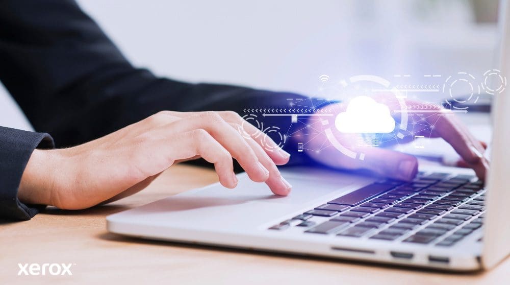 Xerox® Workplace Cloud et Suite : connectivité cloud Les mains d'une personne sont représentées en train de taper sur un clavier d'ordinateur portable, avec une icône de nuage lumineux et des connexions réseau superposées sur l'image, symbolisant la connectivité cloud et les flux de travail numériques.