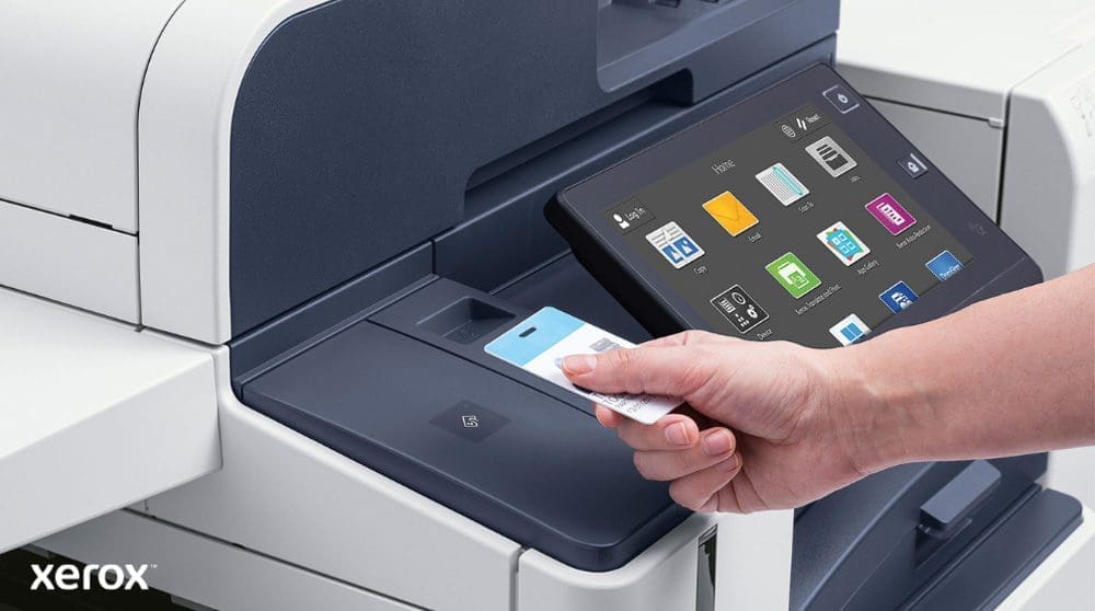 Xerox® Workplace Cloud et Suite : authentification sécurisée et interface intelligente Une main tient une carte de sécurité et la scanne près du lecteur de carte d'une imprimante multifonction Xerox moderne dotée d'un grand écran tactile affichant diverses icônes d'application.